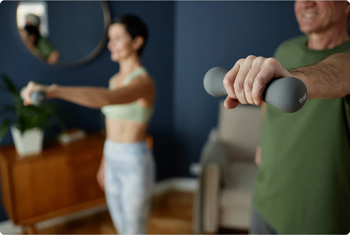 Un hombre y una mujer haciendo ejercicio con mancuernas en casa