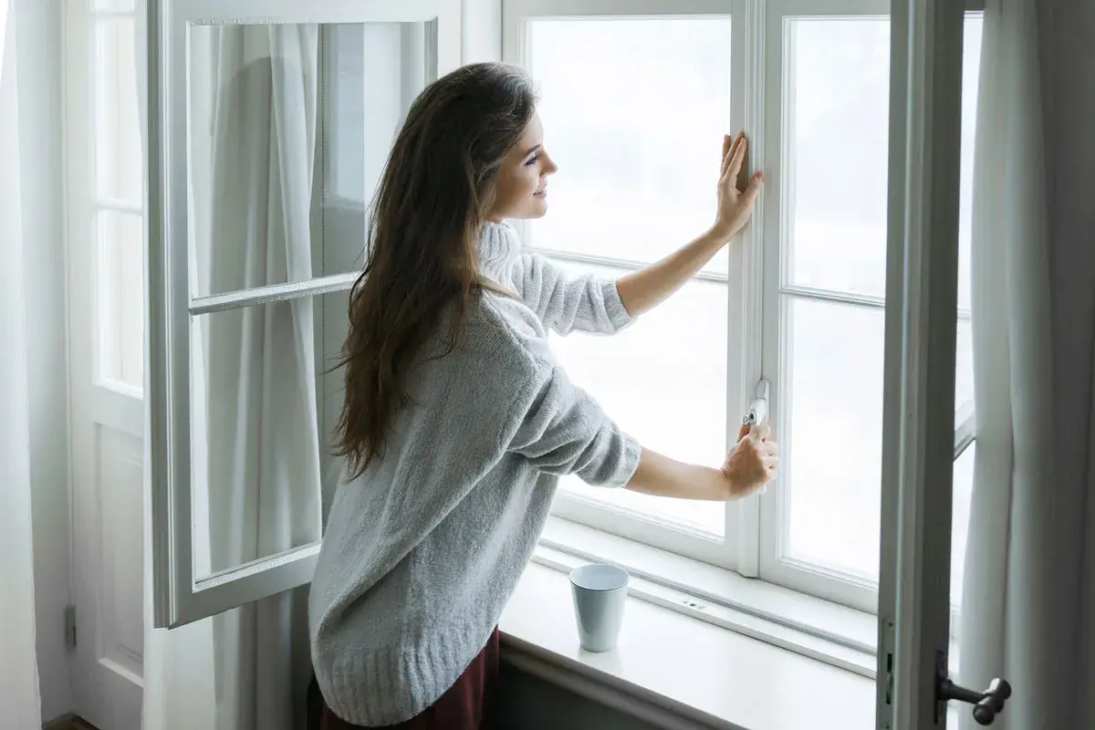 mujer cerrando la ventana de su hogar