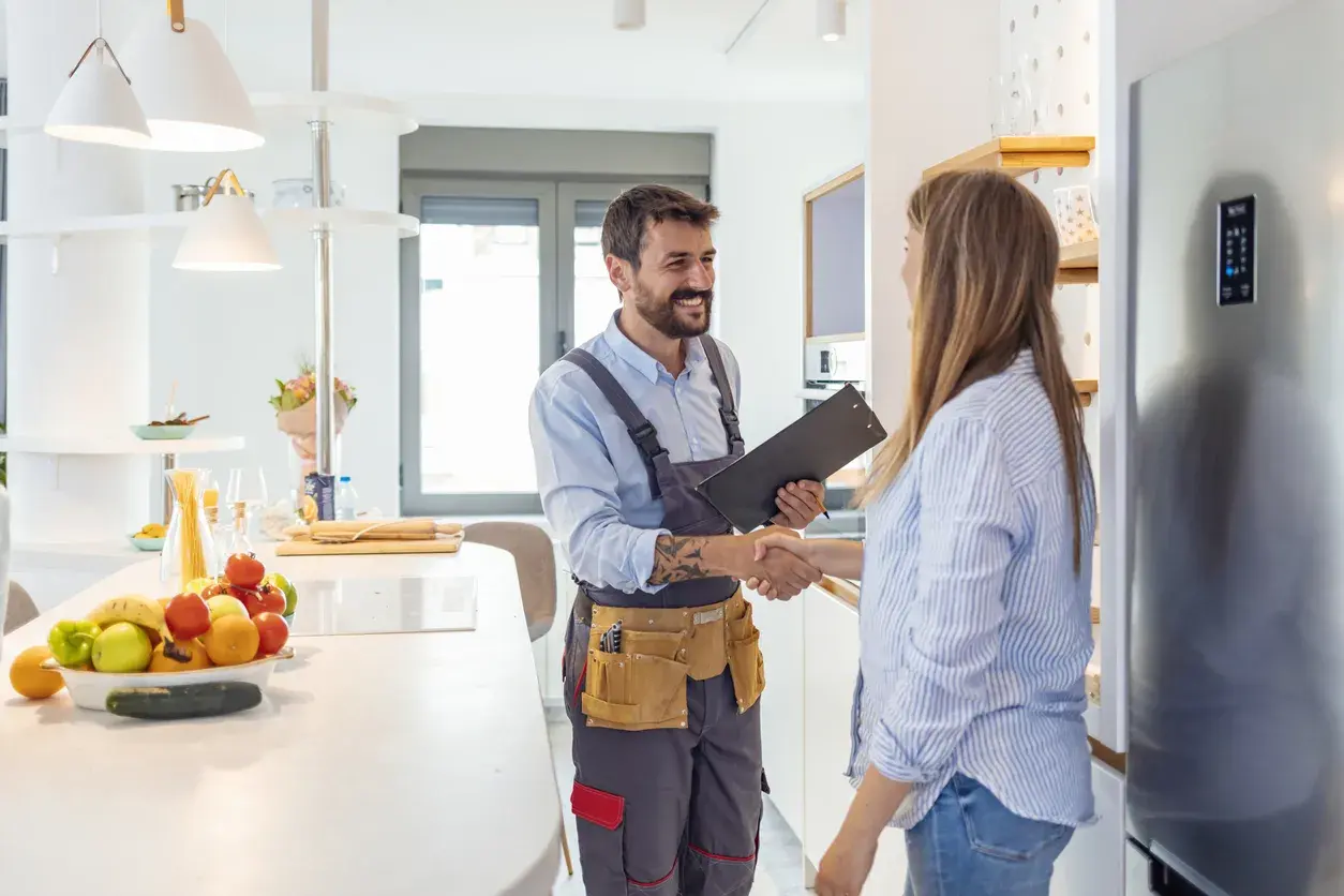 técnico estrechando la mano a mujer en cocina
