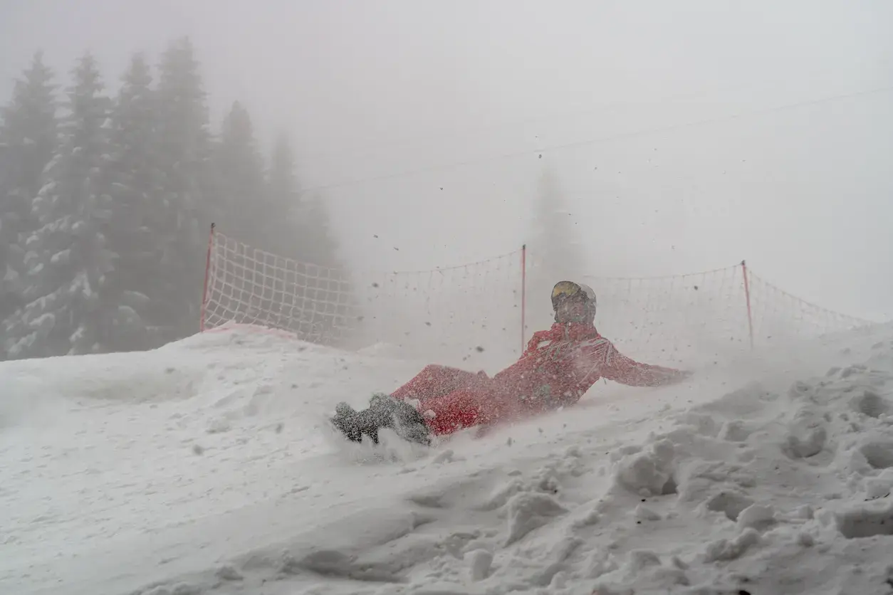 Caída chico haciendo snow en pista con niebla