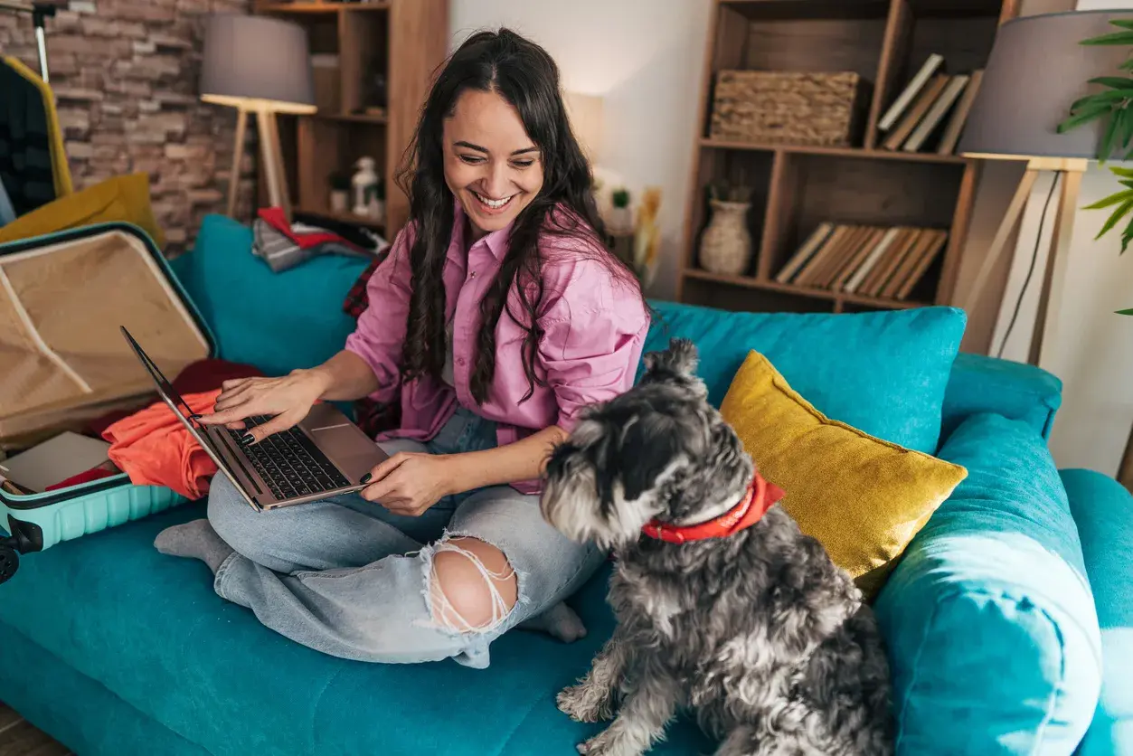 Chica en el sofá con el ordenador con su perro