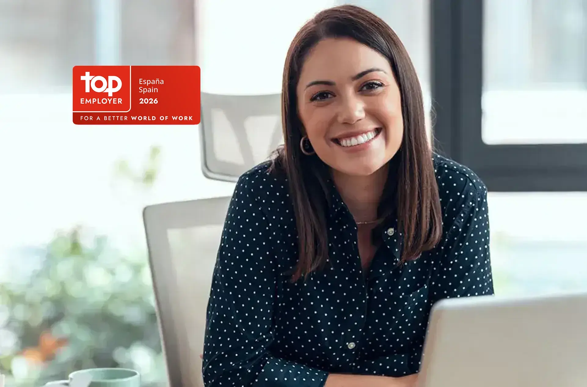 joven sentada en oficina con logo top employer 2026